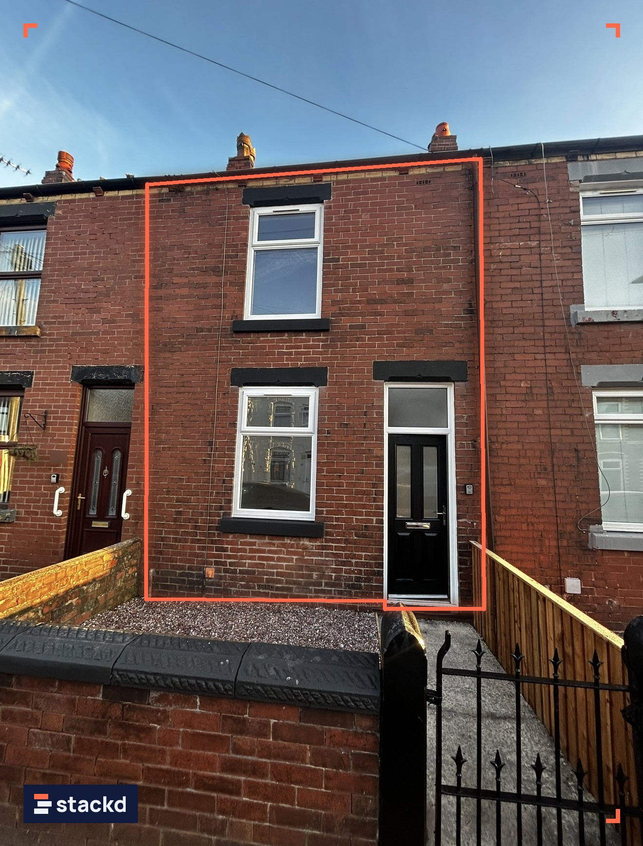 Renovated red-brick mid-terrace house with a new front door, new windows, gravel front garden and timber side fence on a sunny day